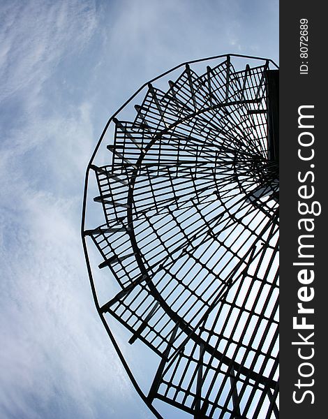 A metal winding staircase against a blue sky.
