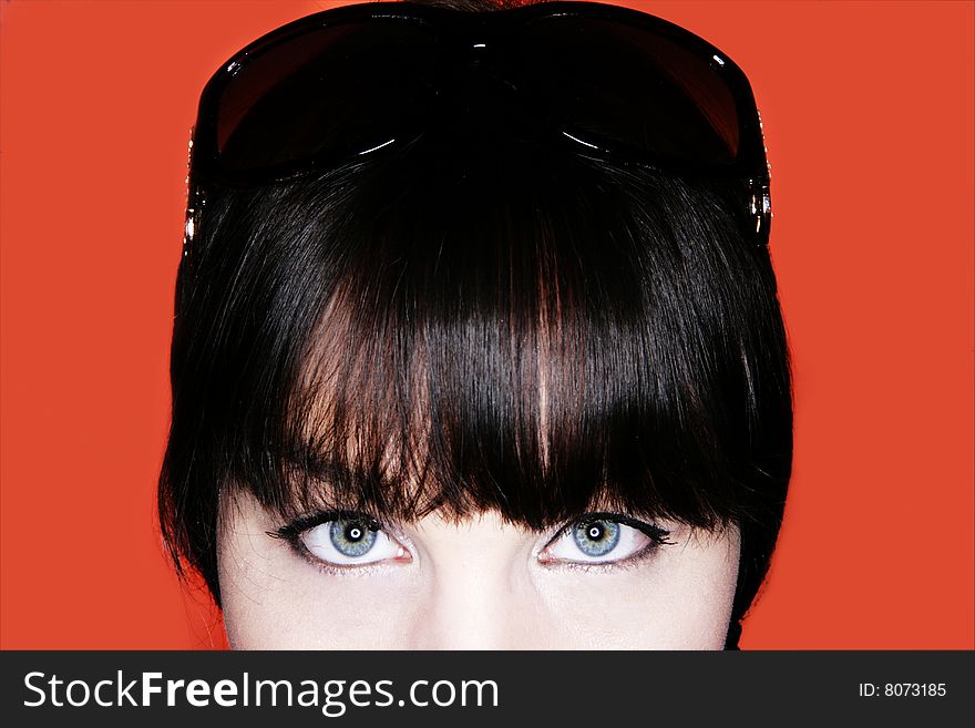 Attractive brunette with sunglasses close up against an orange background