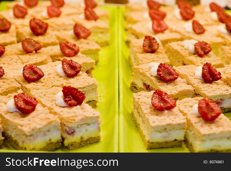 Fresh delicious cream pastries at a market or buffet with fresh strawberries on top