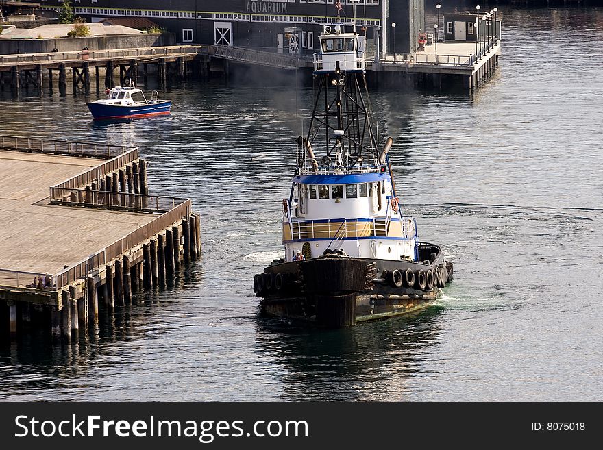 A tugboat leaving a dock by an Aquarium. A tugboat leaving a dock by an Aquarium