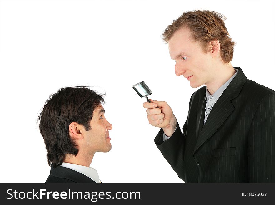 One businessman looks at another through magnifying lens