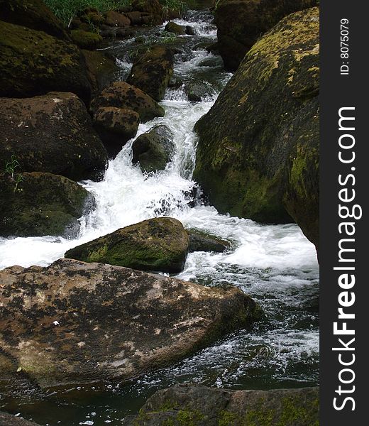 Stream in Western Oregon. Water flowing between large mossy rocks. Stream in Western Oregon. Water flowing between large mossy rocks.