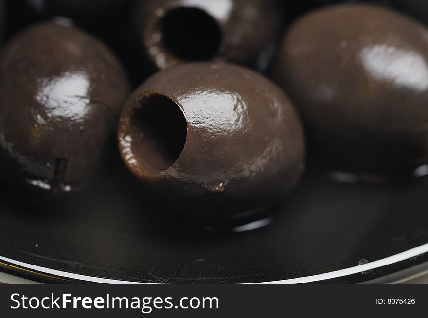 Black olives without the stone on the black plate. Narrow depth of field. Black olives without the stone on the black plate. Narrow depth of field.