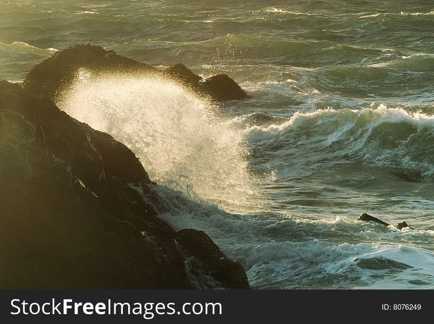Evening ocean waves in the dark rocks