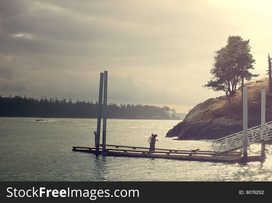 A couple walking a dog on the pier at the Deception pass, Washington. A couple walking a dog on the pier at the Deception pass, Washington