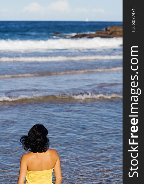 Back view of young woman standing at water's edge on Manly, Sydney. Gazing at the ocean. Back view of young woman standing at water's edge on Manly, Sydney. Gazing at the ocean.