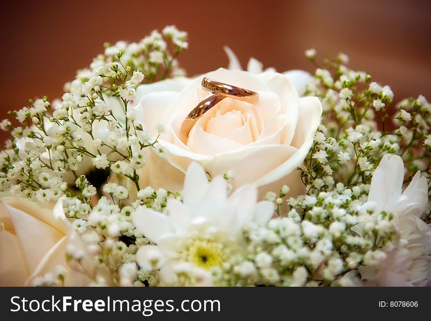 Wedding rings lie in a bouquet of the bride