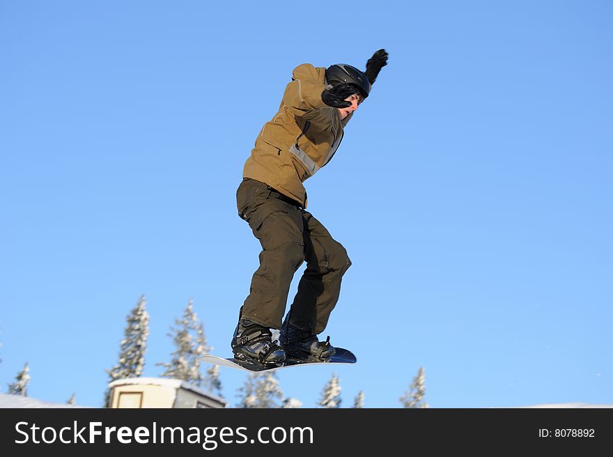 Photo of a young male snowboarder jumping against a blue sky