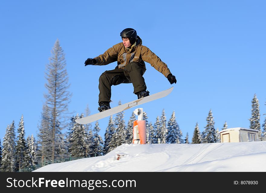 Photo of a young male snowboarder jumping against a blue sky