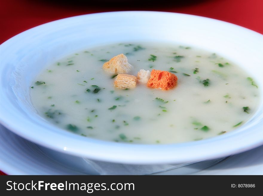 White plate with soup on a red cloth