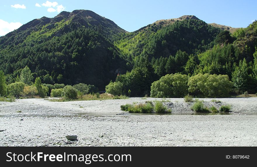 Scenic photo of a riverbed with mountains in the background somewhere in New Zealand