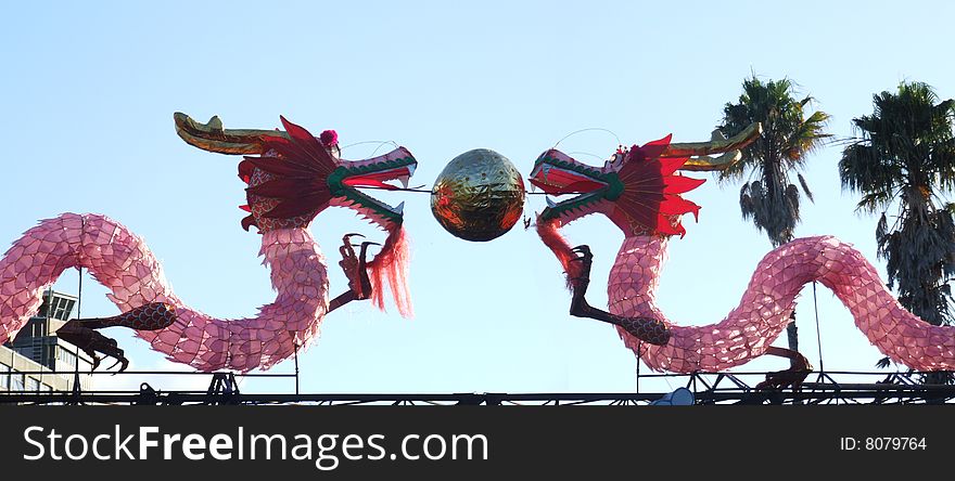 Scenic photo of a pair of chinese dragons with  office buildings in the background somewhere in New Zealand