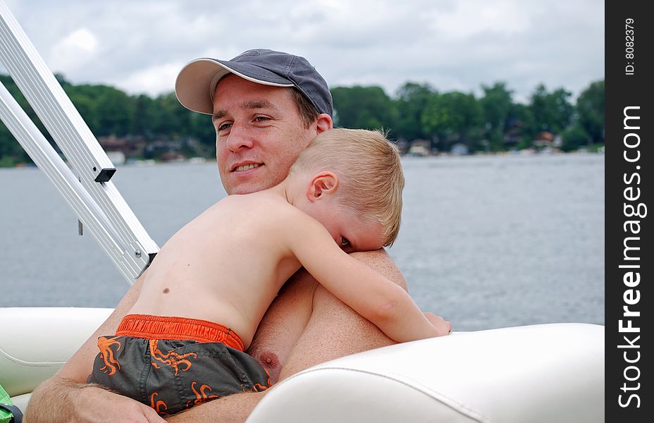 A father and son share a hug while on a boat ride. A father and son share a hug while on a boat ride