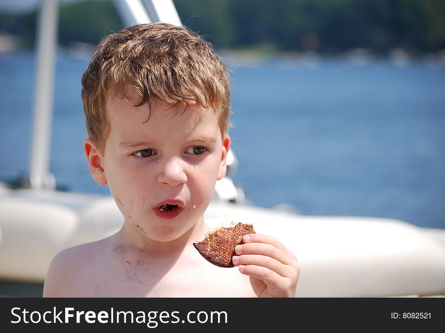 A little boy makes a mess with his cookie on the boat. A little boy makes a mess with his cookie on the boat