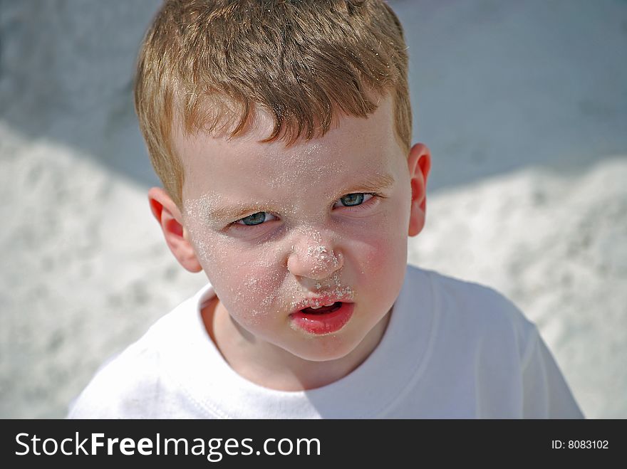 A little boy shows his sandy face at the beach. A little boy shows his sandy face at the beach