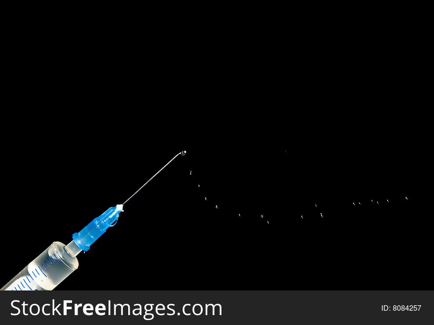 Syringe and drops of medicine on a black background