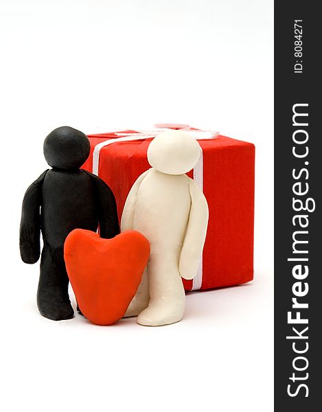 Two Plasticine persons against a box with a gift and with heart