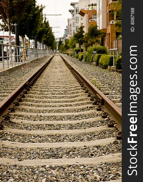 Railroad tracks running straight alongside a city street. Railroad tracks running straight alongside a city street