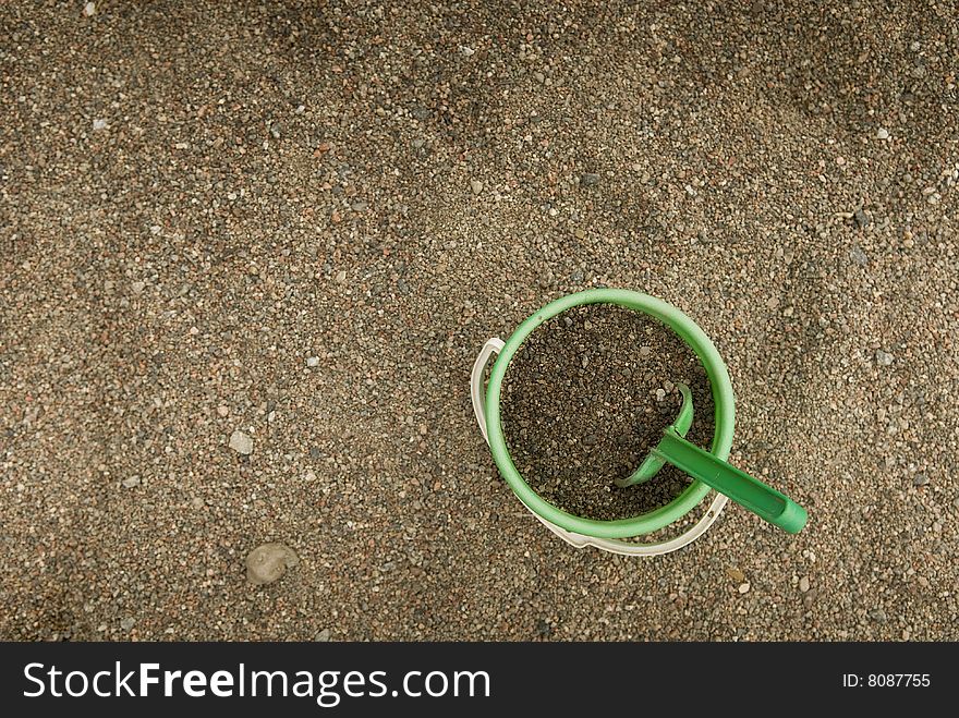 Green sand bucket standing in a sandbox