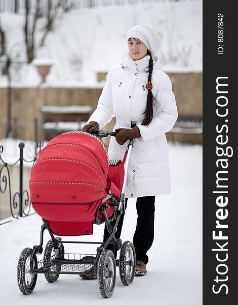 Woman in white jacket with red baby carriage outdoors - shallow DOF. Woman in white jacket with red baby carriage outdoors - shallow DOF