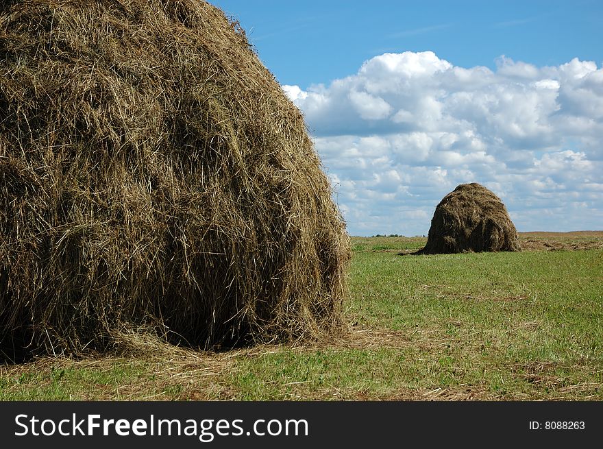 Haystacks in the field, clouds in the sky. Haystacks in the field, clouds in the sky