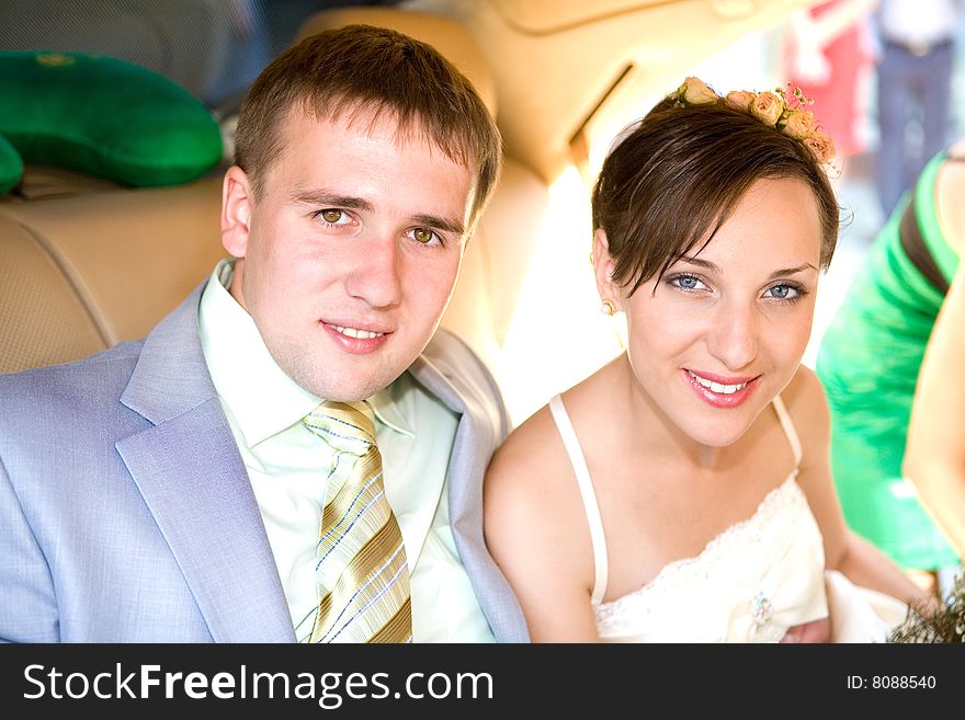 Portrait smiling groom and bride in wedding car