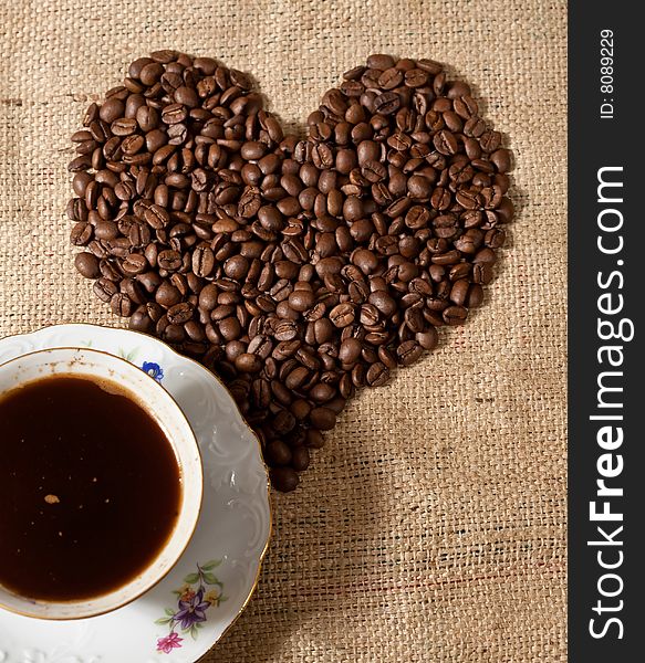 Heart shape made from coffee beans and cup of coffee