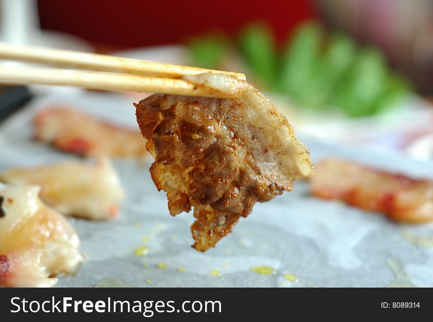 Welldone mutton slice held by chopsticks.