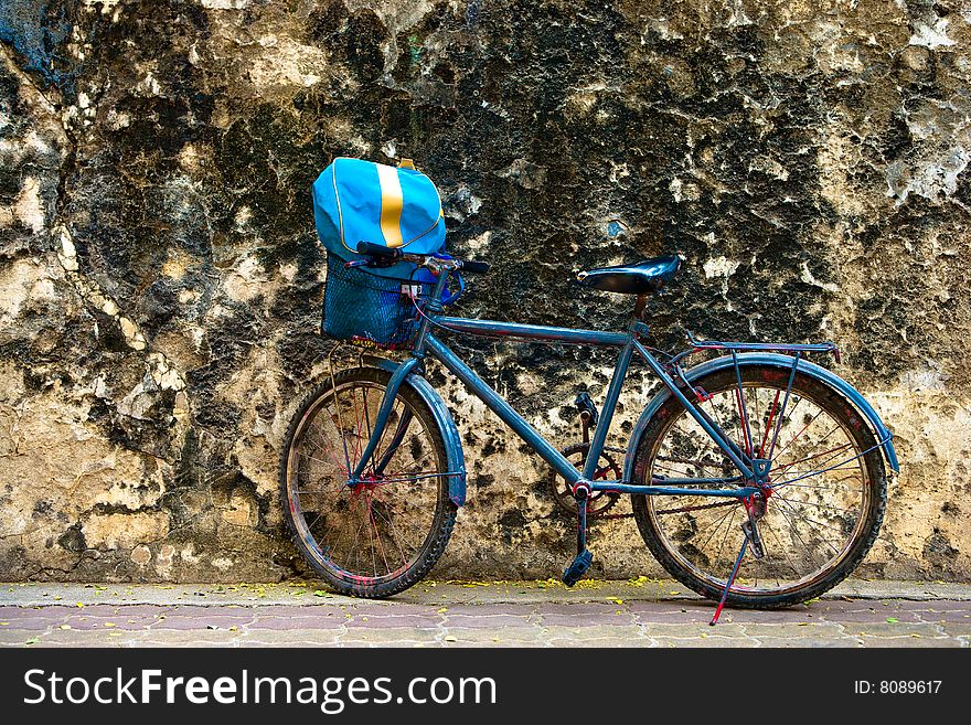 Old bicycle agints dirty old wall.