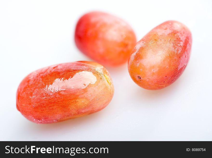 Three red grapes on white background with soft focus