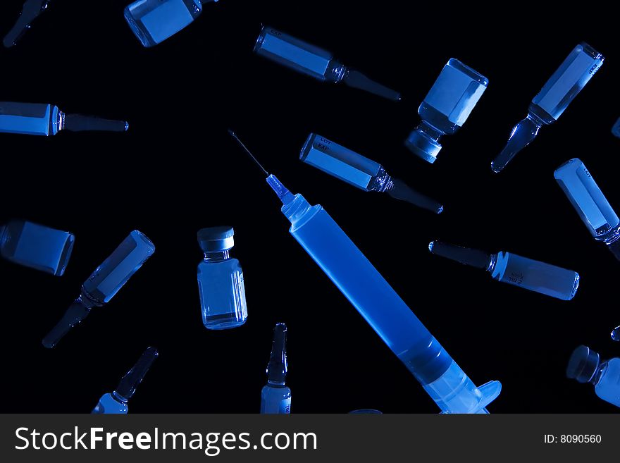 Isolated in a black backround are vials, ampules and syringe.