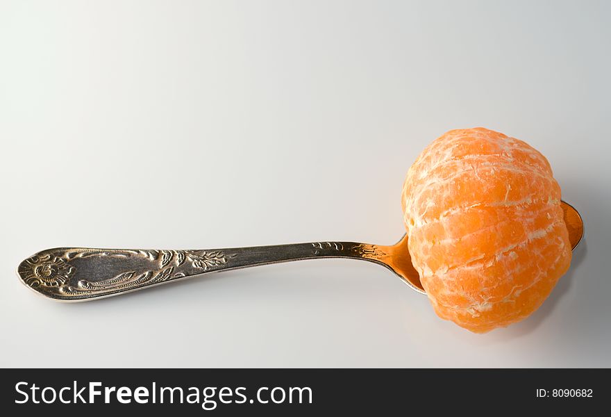 Metal teaspoon holding a half of tangerine from above