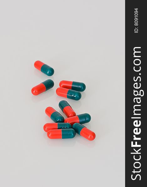 Ten scattered red and green medical capsules