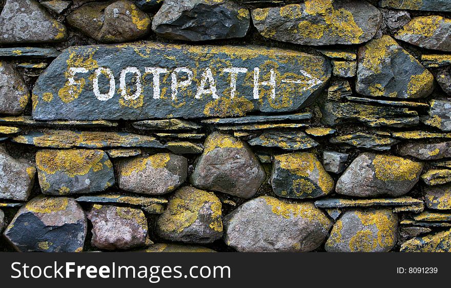 Footpath sign on stone wall