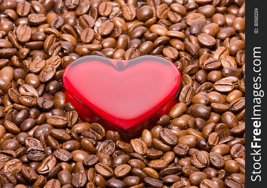 Glossy red heart made from glass laying in the coffee beans. Glossy red heart made from glass laying in the coffee beans