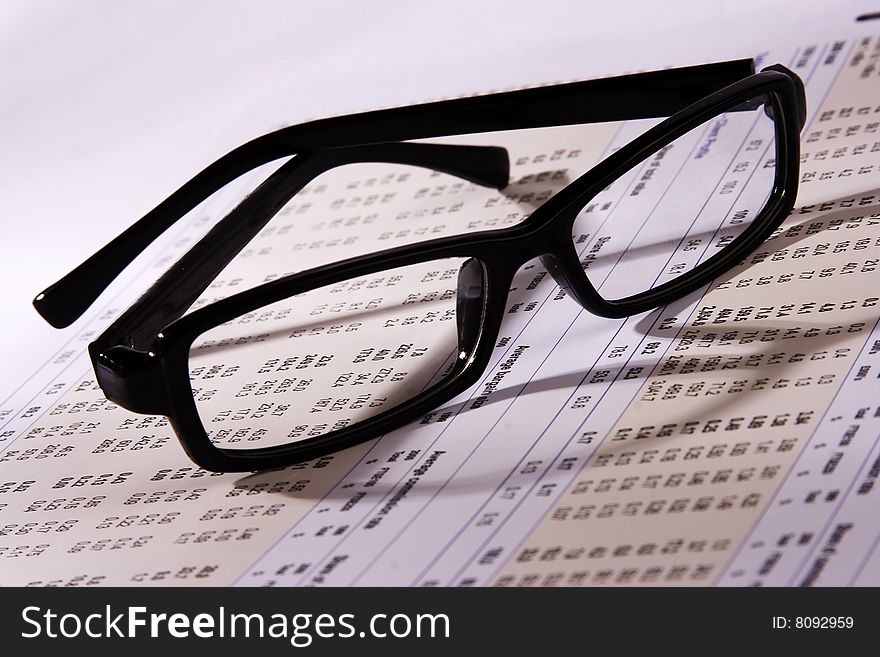 Eyeglasses on a financial statement with side light.