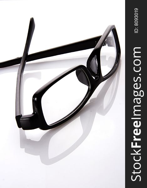 A black frame eyeglasses in plain white background with reflection.