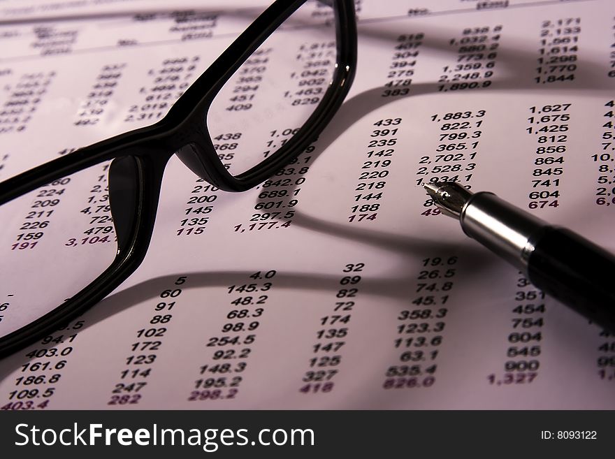 A Financial statement with eyeglasses and fountain pen.