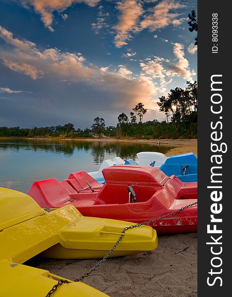 Pedal boats of various colors lined up at lake bank
