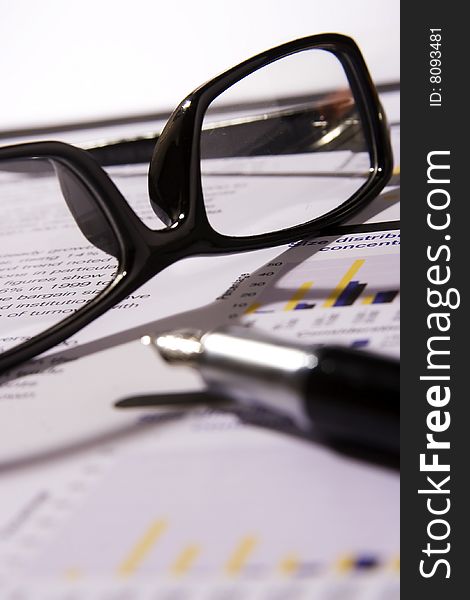 A Financial statement with a black frame eyeglasses and fountain pen.