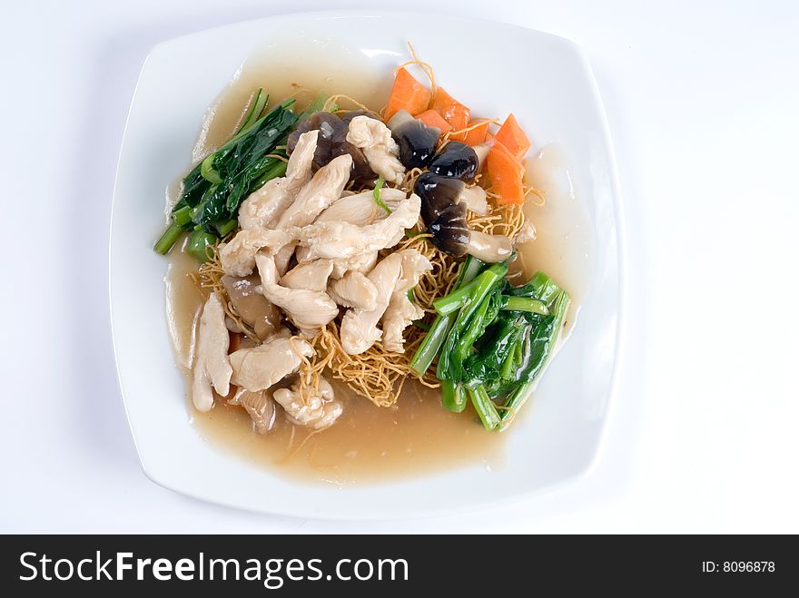 Glazed chicken over rice noodles with vegetables