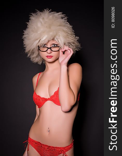Attractive girl in glasses and furry hat over black background