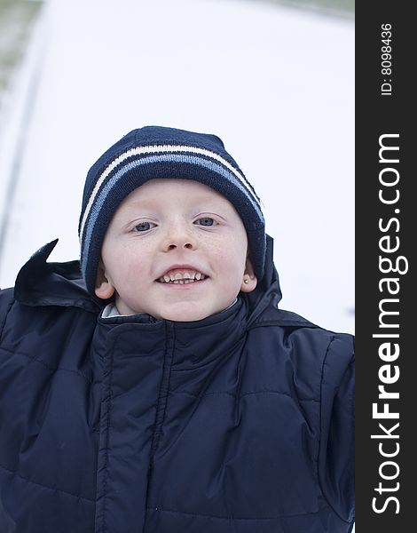 Mischievous boy in the winters snow wearing a hat