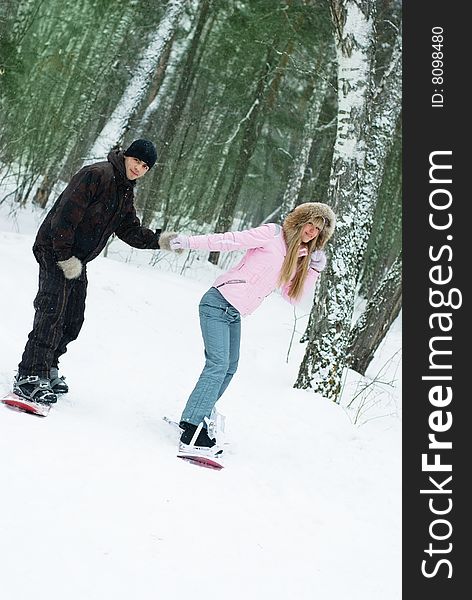 Happy beautiful young couple snowboarding on the mountain in wintertime and having fun. Happy beautiful young couple snowboarding on the mountain in wintertime and having fun