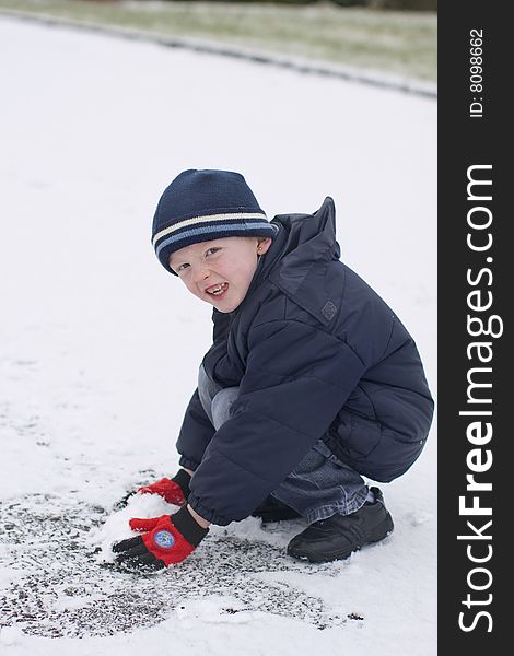 Little boy wearing a blue hat playing in the snow. Little boy wearing a blue hat playing in the snow