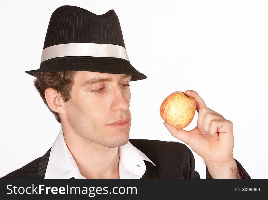 Young man looking at delicious apple with hat on. Young man looking at delicious apple with hat on