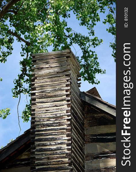 An old log cabin chimney on a spring day