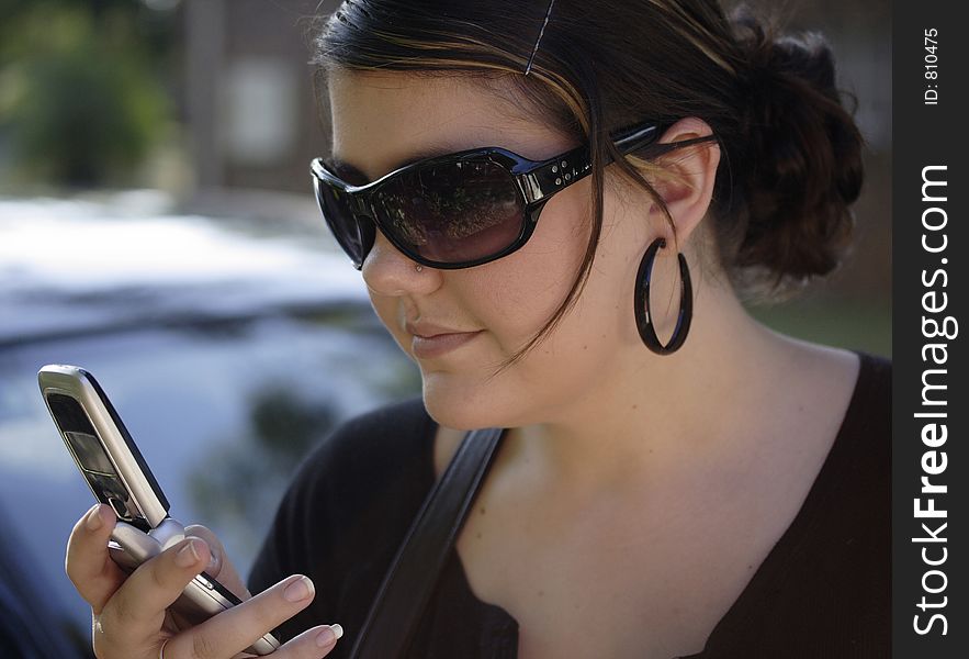 Image of a young woman checking her cell phone. Image of a young woman checking her cell phone