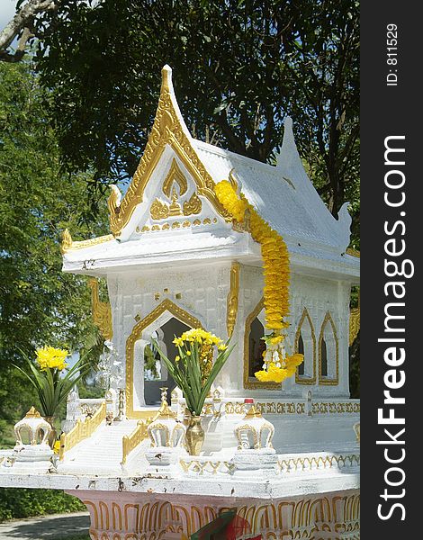 Traditional white and gold spirit house among trees in Thailand. Traditional white and gold spirit house among trees in Thailand