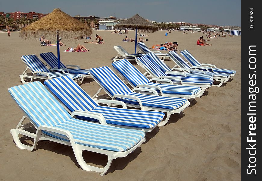 File of eight beach chairs and two umbrellas with two chairs each one behind. File of eight beach chairs and two umbrellas with two chairs each one behind